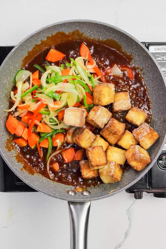 veggies and tofu cubes added to the sauce in the skillet.