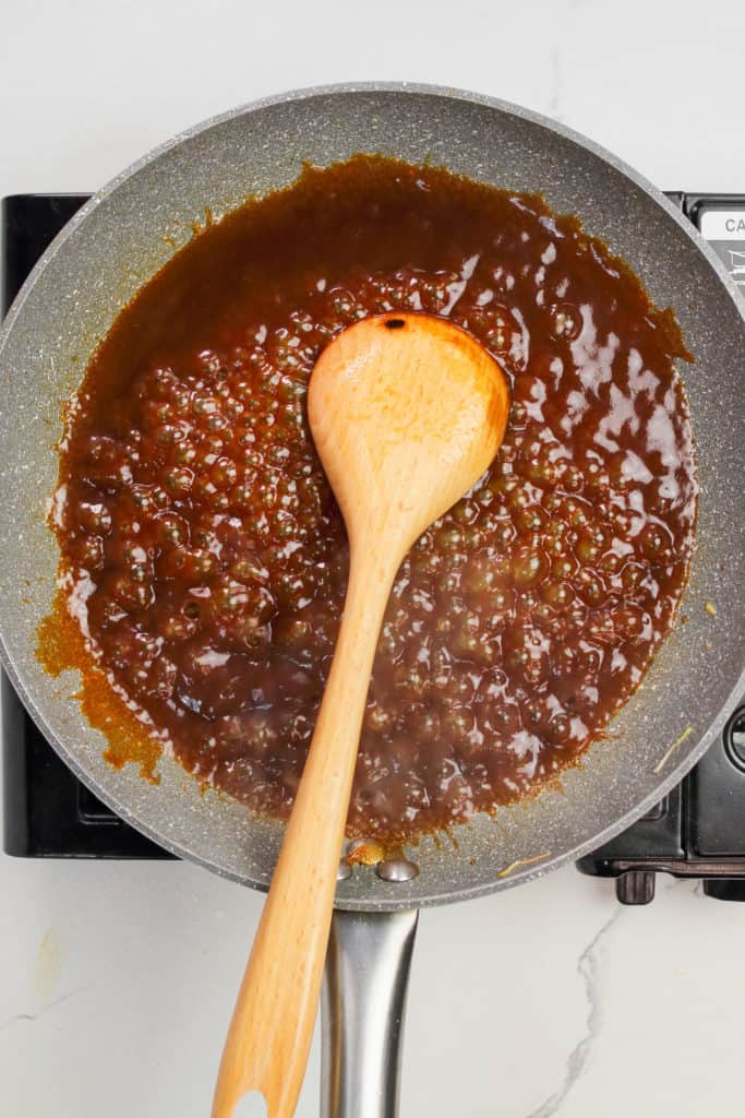brown sauce in a skillet with a wooden spoon.