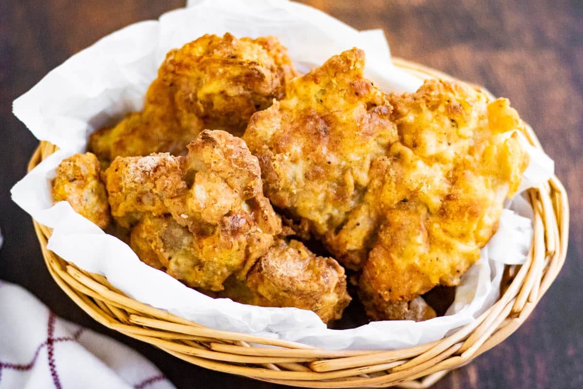 Air fryer fried chicken thighs in a basket lined with parchment paper.