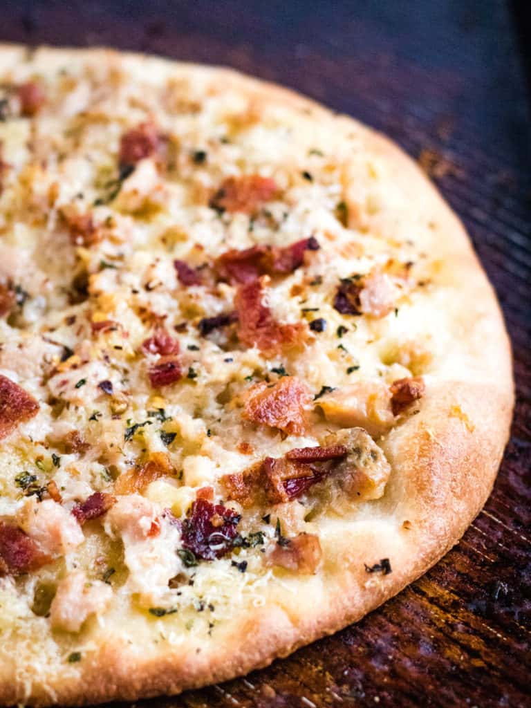White clam pizza with bacon on a wooden table.
