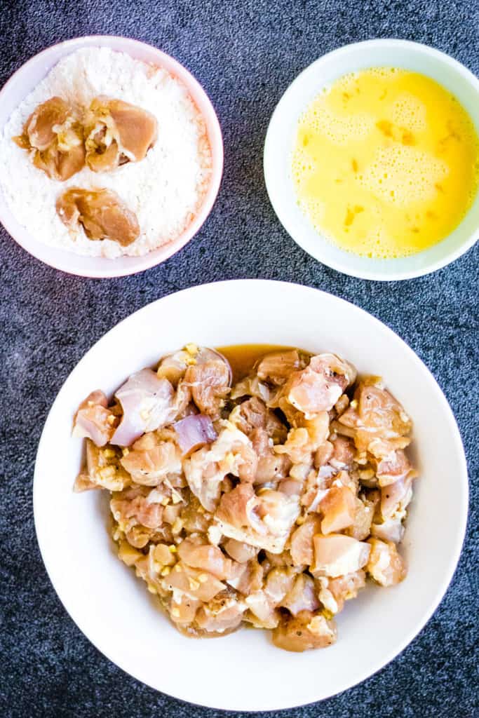 A delicious bowl of air fryer orange chicken with rice and sauce on a table.