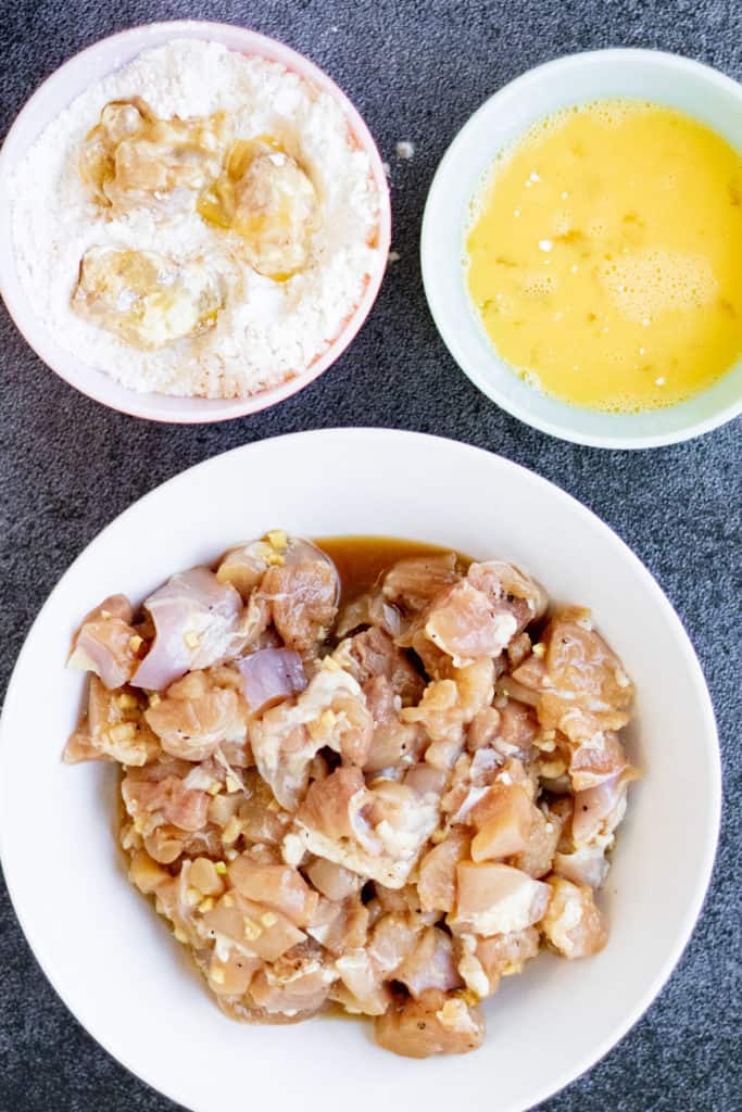 A bowl of air fried orange chicken with eggs and other ingredients.