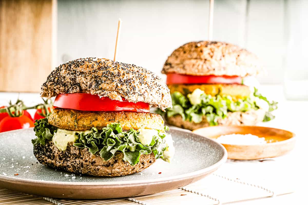 Low angle shot of 2 chickpea burgers on seeded buns with all the fixings.