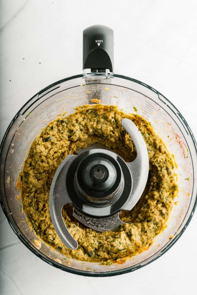 A food processor filled with a mixture of greens and chickpea burgers.