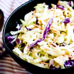 Low angle shot of creamy coleslaw in a black bowl.