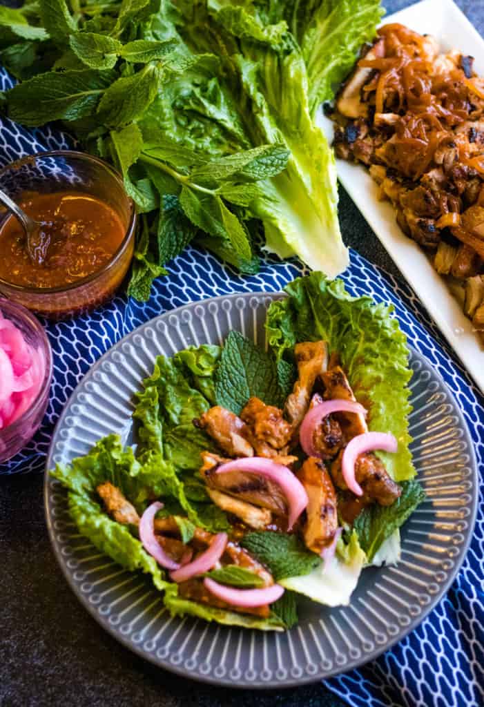 overhead shot of gochujang chicken with lettuce, fresh mint, pickled onions, and ssamjang.