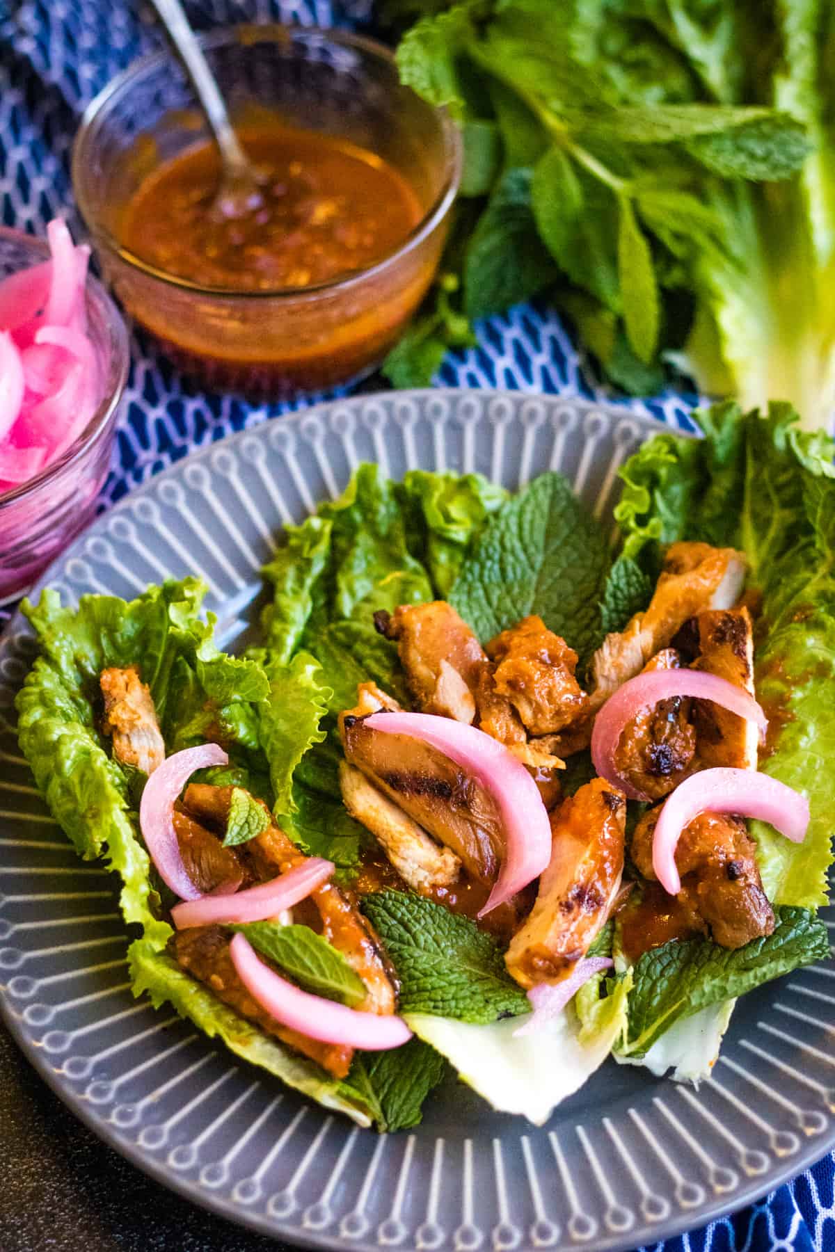 Korean gochujang chicken lettuce wraps on a grey and white plate.