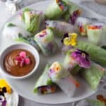 summer rolls on a platter with peanut sauce.
