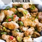 A bowl of air fryer salt and pepper chicken pieces garnished with sliced green onions and red chili peppers, with a text overlay reading "Air Fryer Salt and Pepper Chicken.