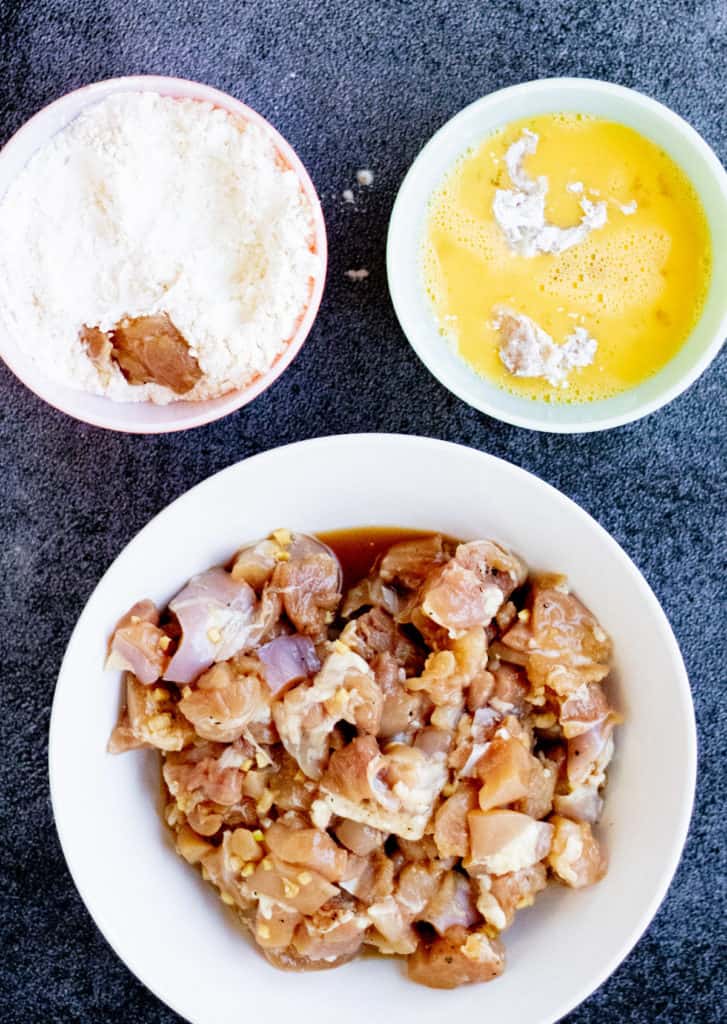 A bowl of chicken and rice with a side of sauce, served alongside another bowl of rice.