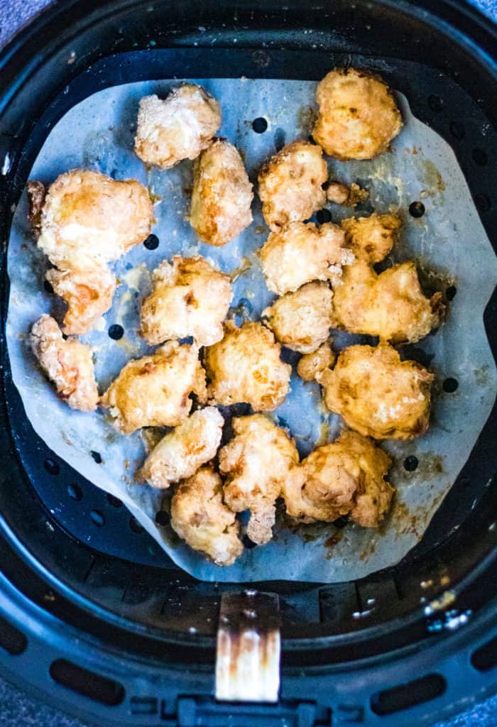 Chicken nuggets in an air fryer seasoned with salt and pepper.