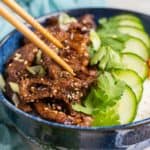 Low angle, closeup photo of beef bulgogi in a blue bowl.