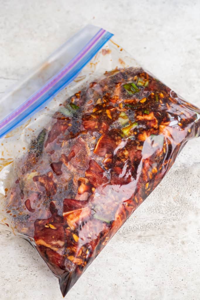 Meat and marinade ingredients in a ziploc bag all mixed up and sealed.
