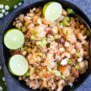 overhead shot of Thai fried rice with pineapple and chicken in a black bowl with lime halves