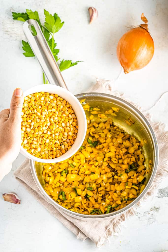 A person is pouring a bowl of corn into a pan.