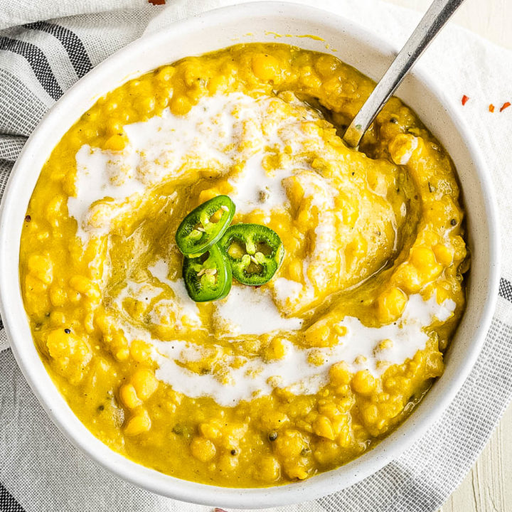 overhead shot of a bowl of dal garnished with coconut milk and sliced green chiles