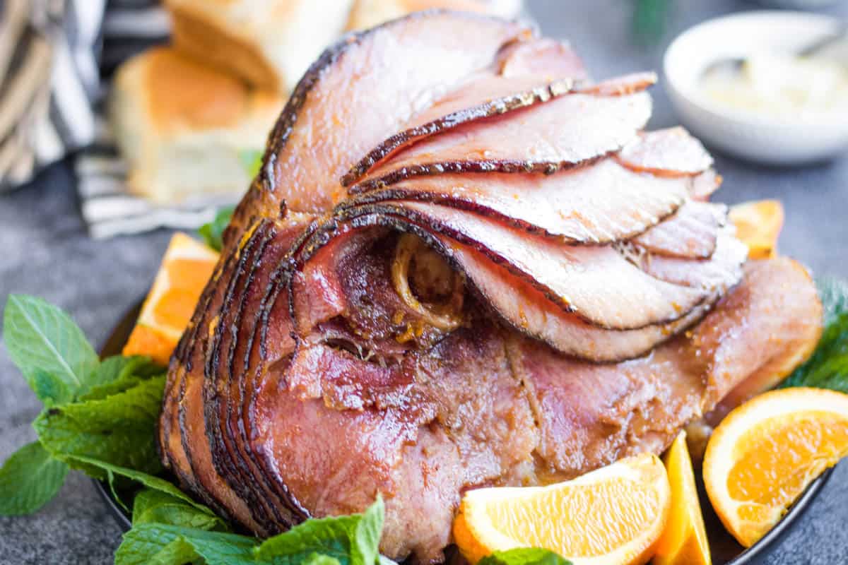 spiral cut ham with orange wedges and fresh green herbs