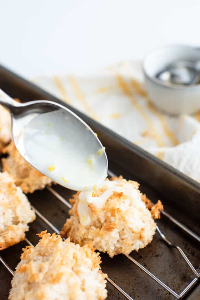 Coconut macaroons on a baking sheet with a scoop of icing.