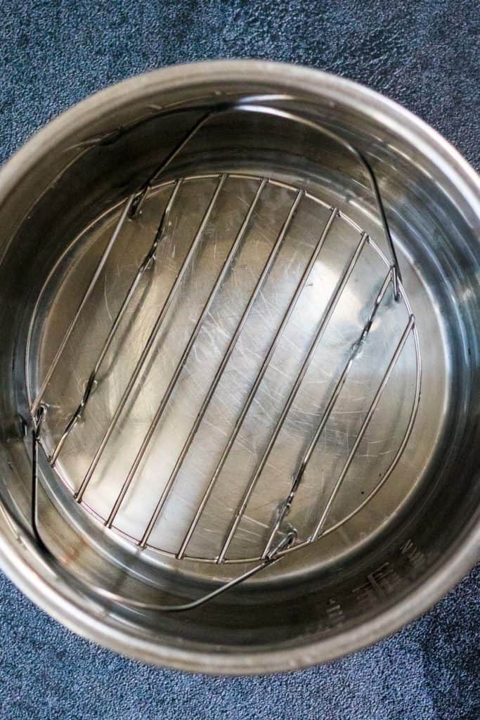 A stainless steel pan with a wire basket used for cooking pollo pibil.