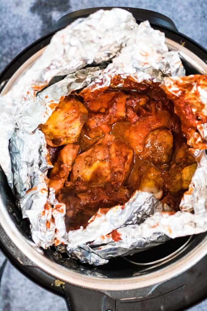 A slow cooker filled with pollo pibil wrapped in foil.