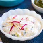 A bowl of cucumber raita with radishes and a bowl of sauce.