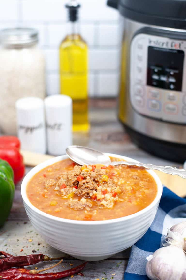 Low angle shot of a bowl of stuffed pepper soup with the instant pot behind it
