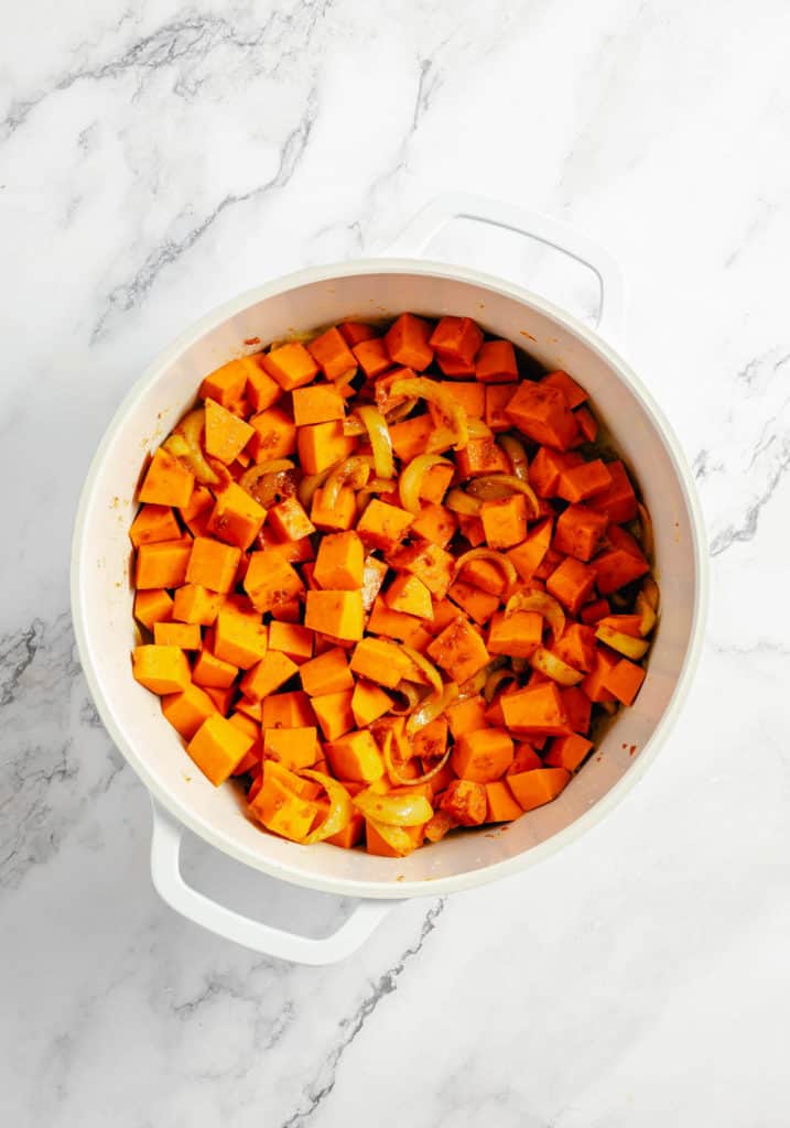 Roasted sweet potatoes in a Thai pumpkin curry on a marble countertop.