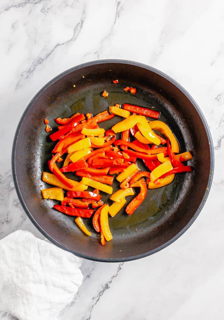 Fried peppers in a frying pan on a marble countertop, infused with Thai pumpkin curry.