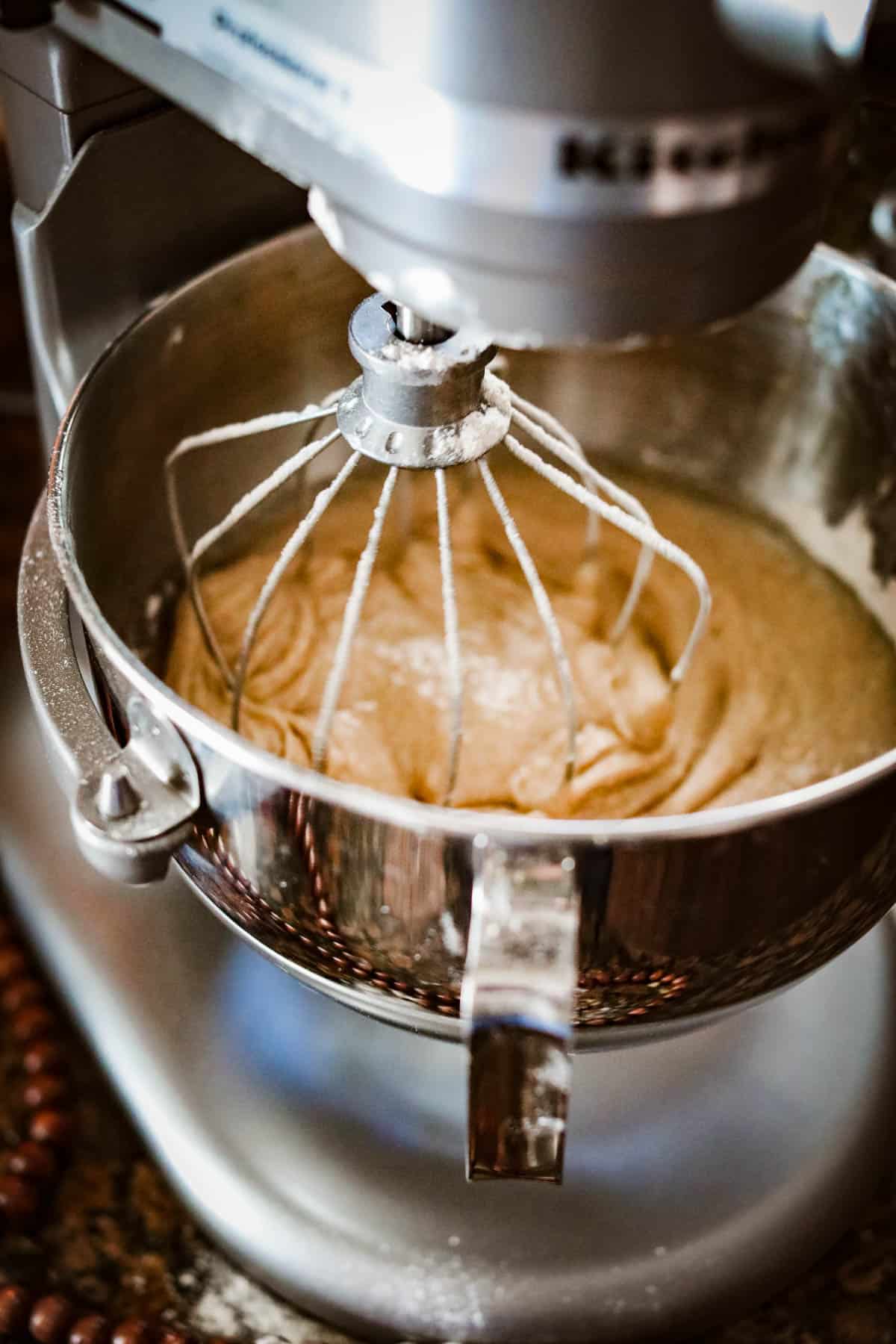 A Kitchenaid mixer with an apple cider donut cake batter in it.