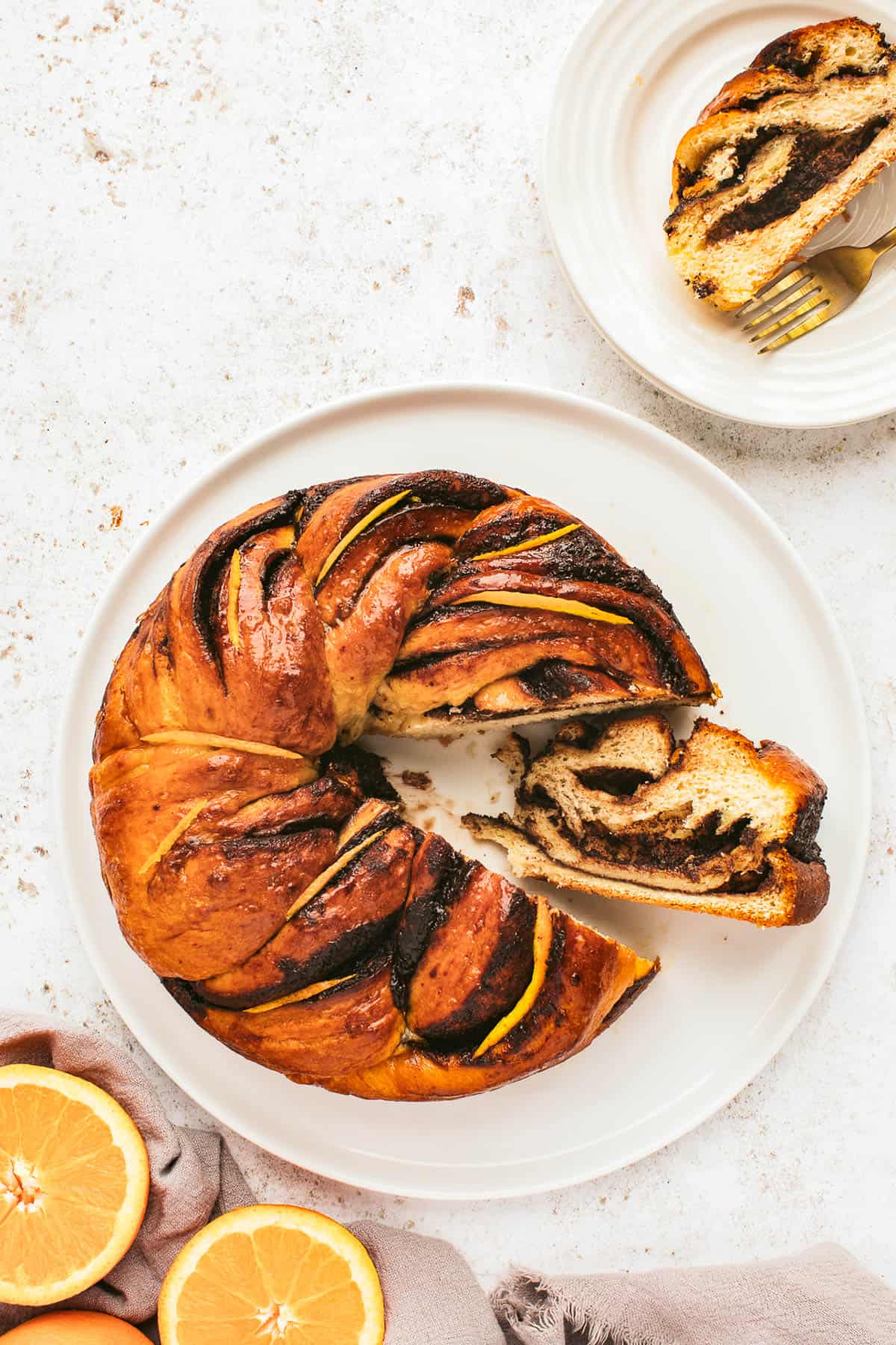 overhead shot of an orange chocolate babka wreath with a wedge taken out and turned on its side so that you can see the swirls of chocolate inside.