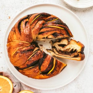 Overhead shot of chocolate orange babka wreath with one slice cut and turned on its side so you can see the inside.