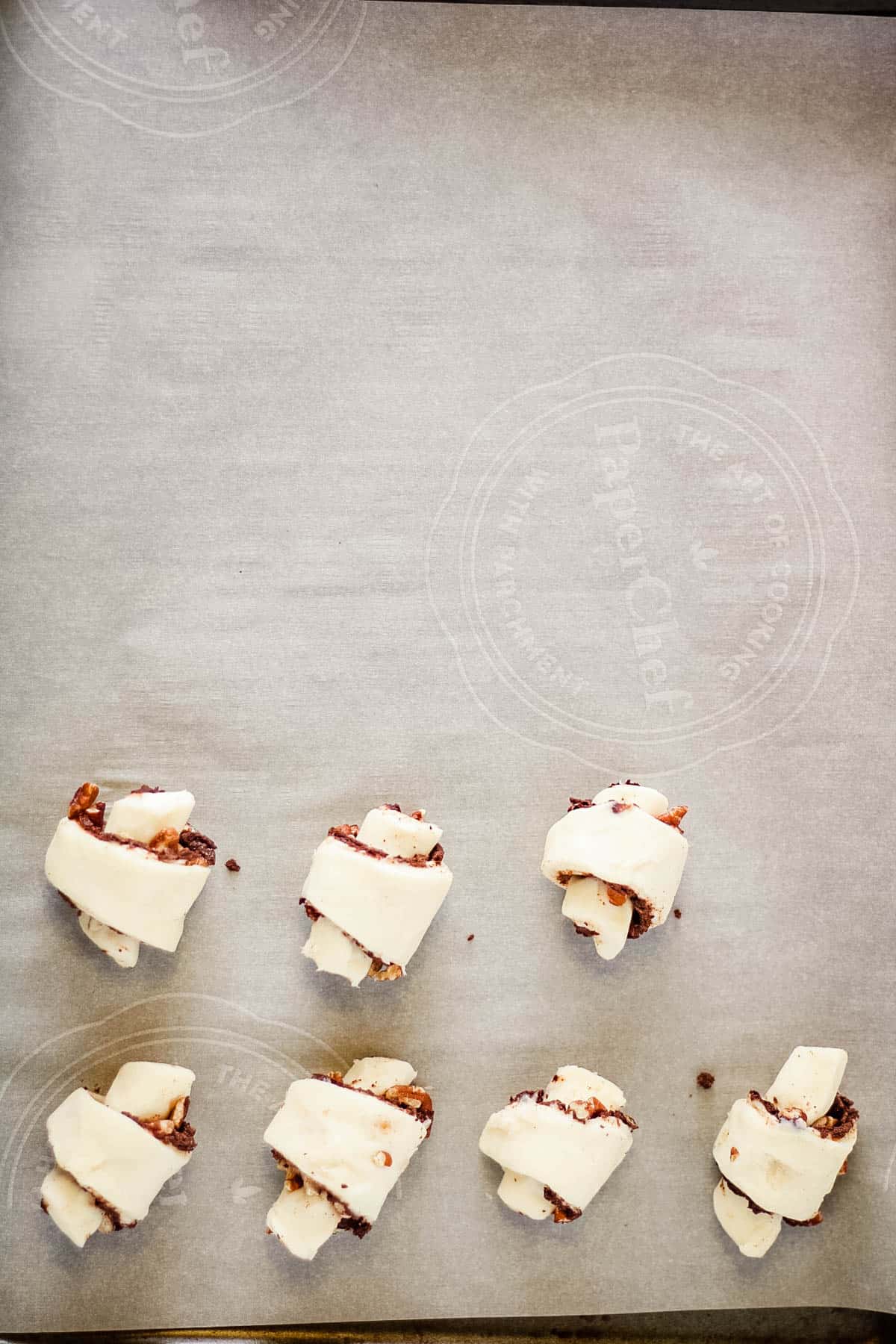 Filled rugelach on a baking sheet.
