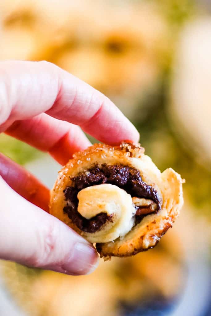 A single chocolate filled rugelach being held up in a hand