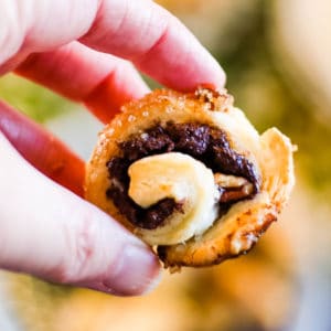 close up shot of a chocolate and pecan filled rugelach in a woman's hand