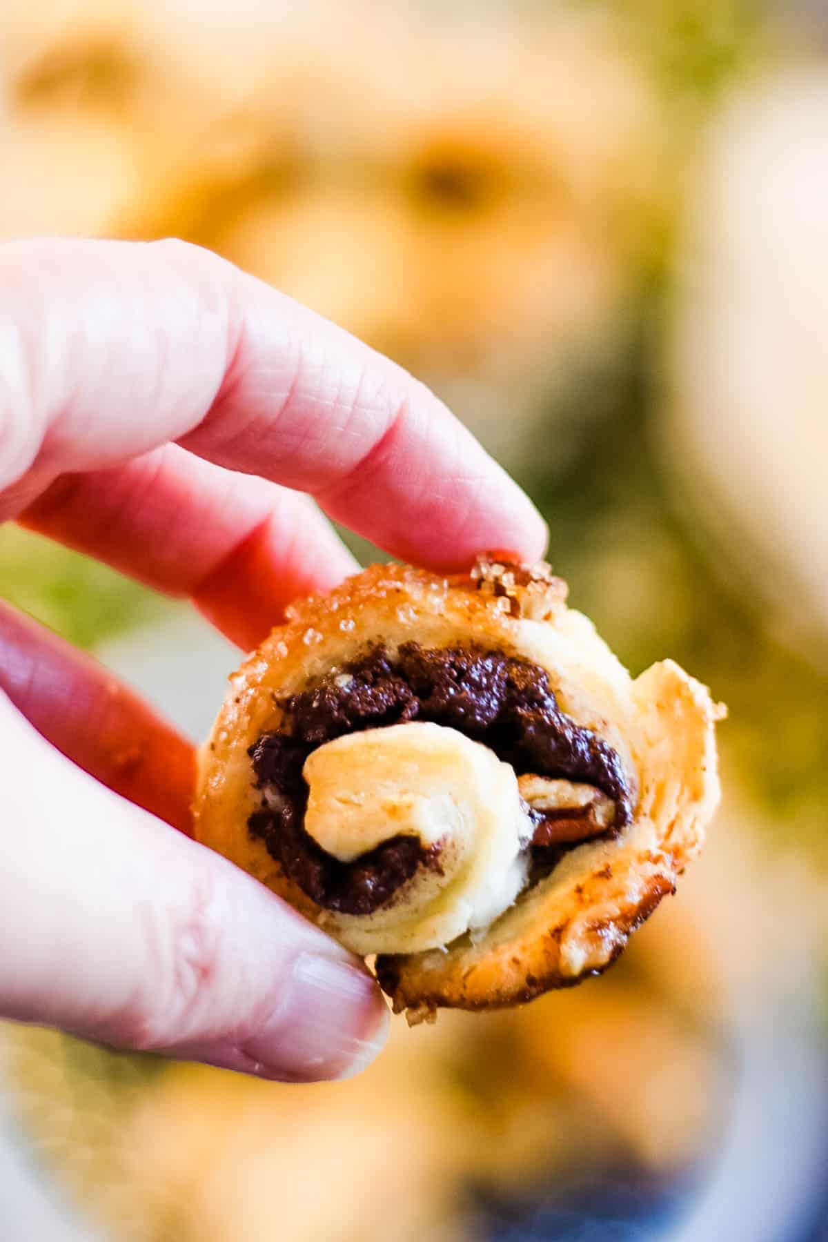 A person holding up a rugelach pastry.