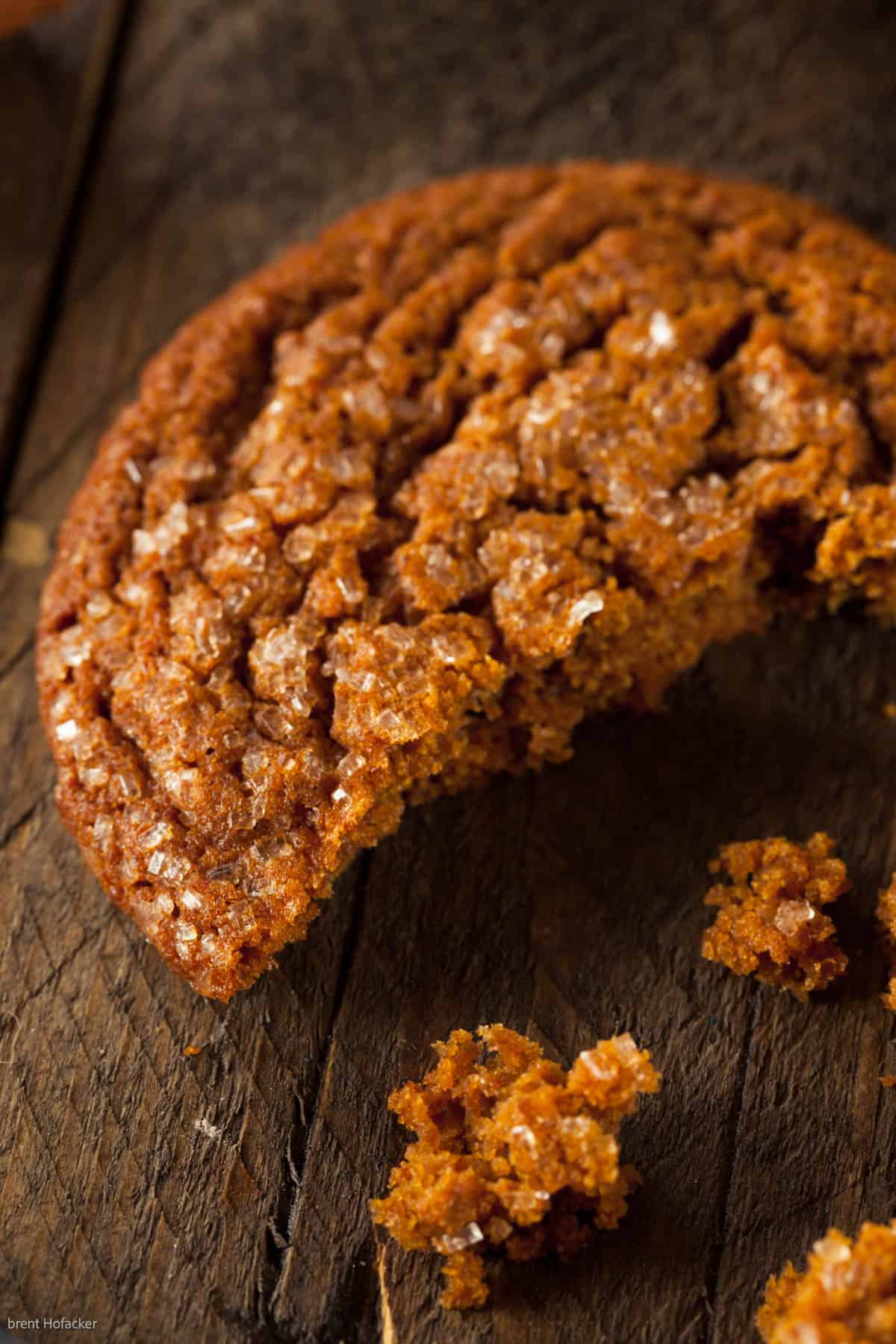 low angle shot of a broken ginger snap cookie with crumbs on a wooden table