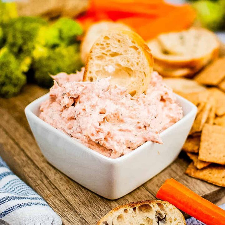 low angle shot of a bowl of smoked salmon dip with baguette slices and crackers