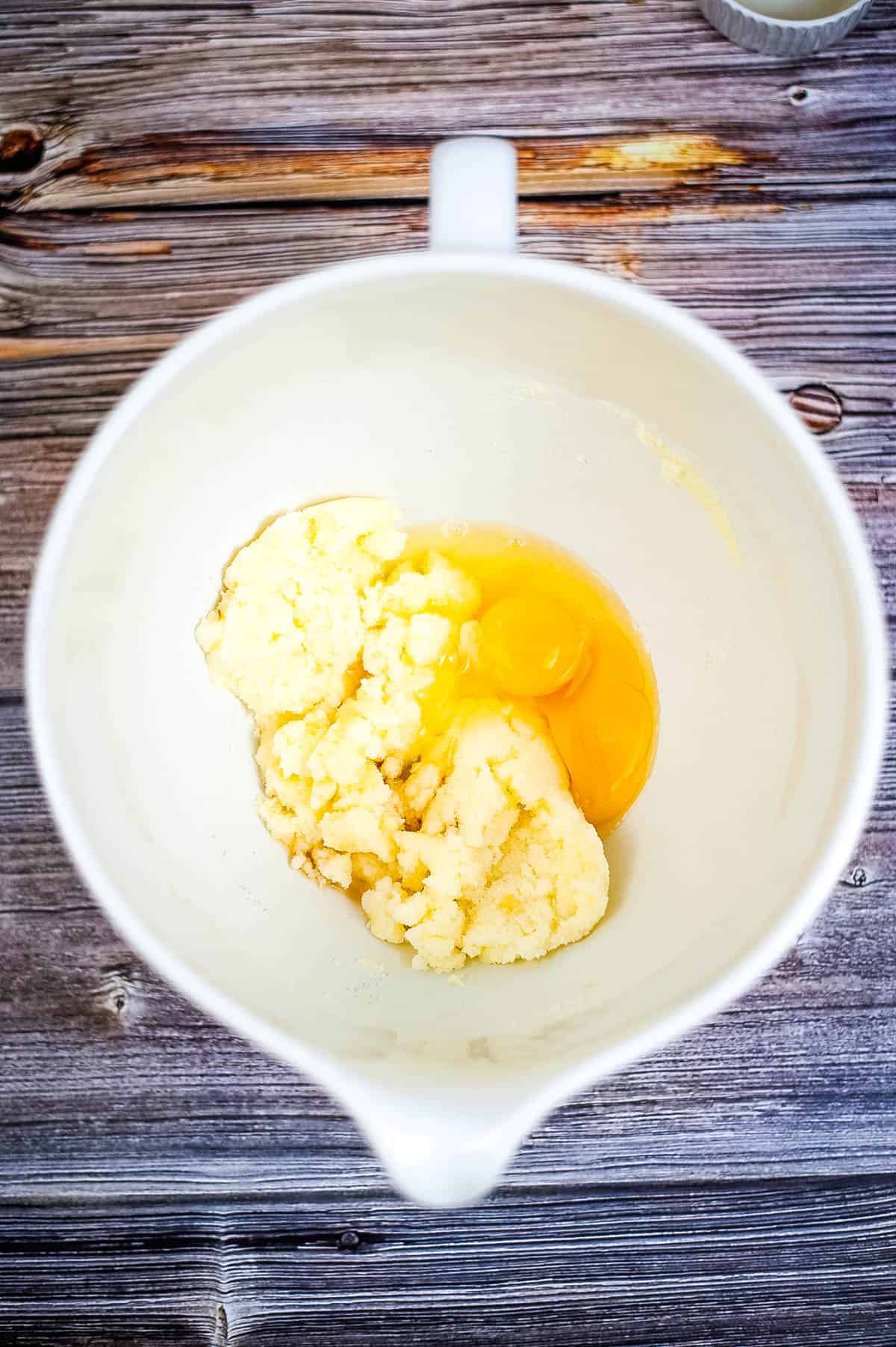 A white bowl with creamed butter and sugar and eggs.