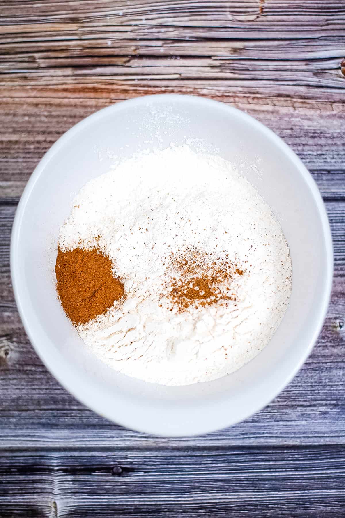 A festive white bowl filled with cinnamon and powdered sugar, perfect for serving eggnog bundt cake.