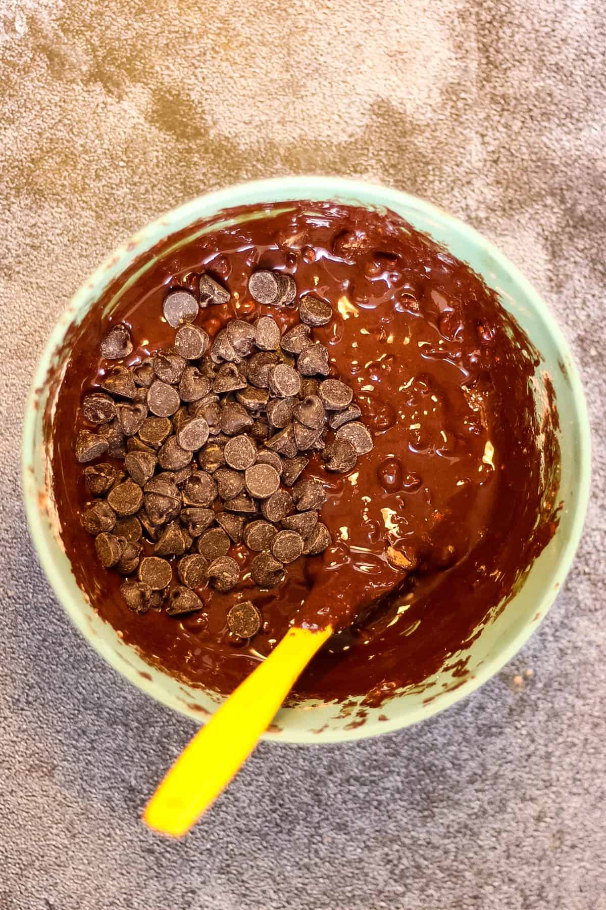 A bowl of flourless chocolate batter with a yellow spoon.