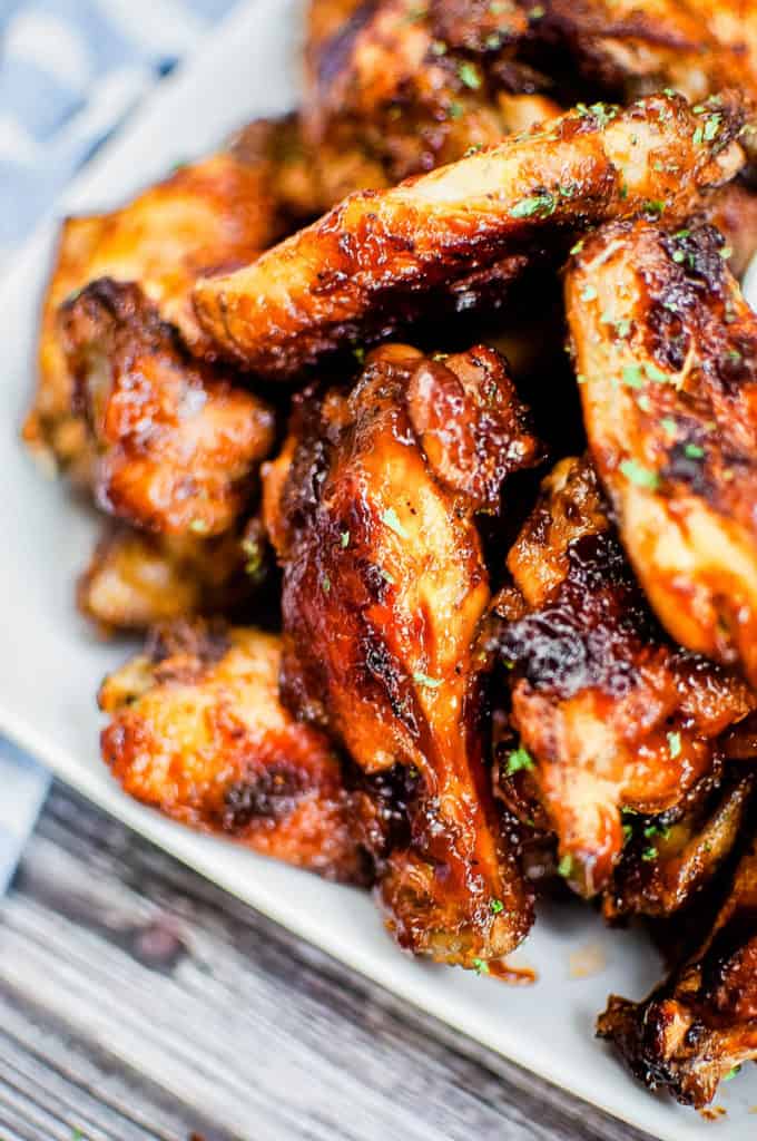 low angle, closeup shot of barbecue chicken wings piled on a white platter