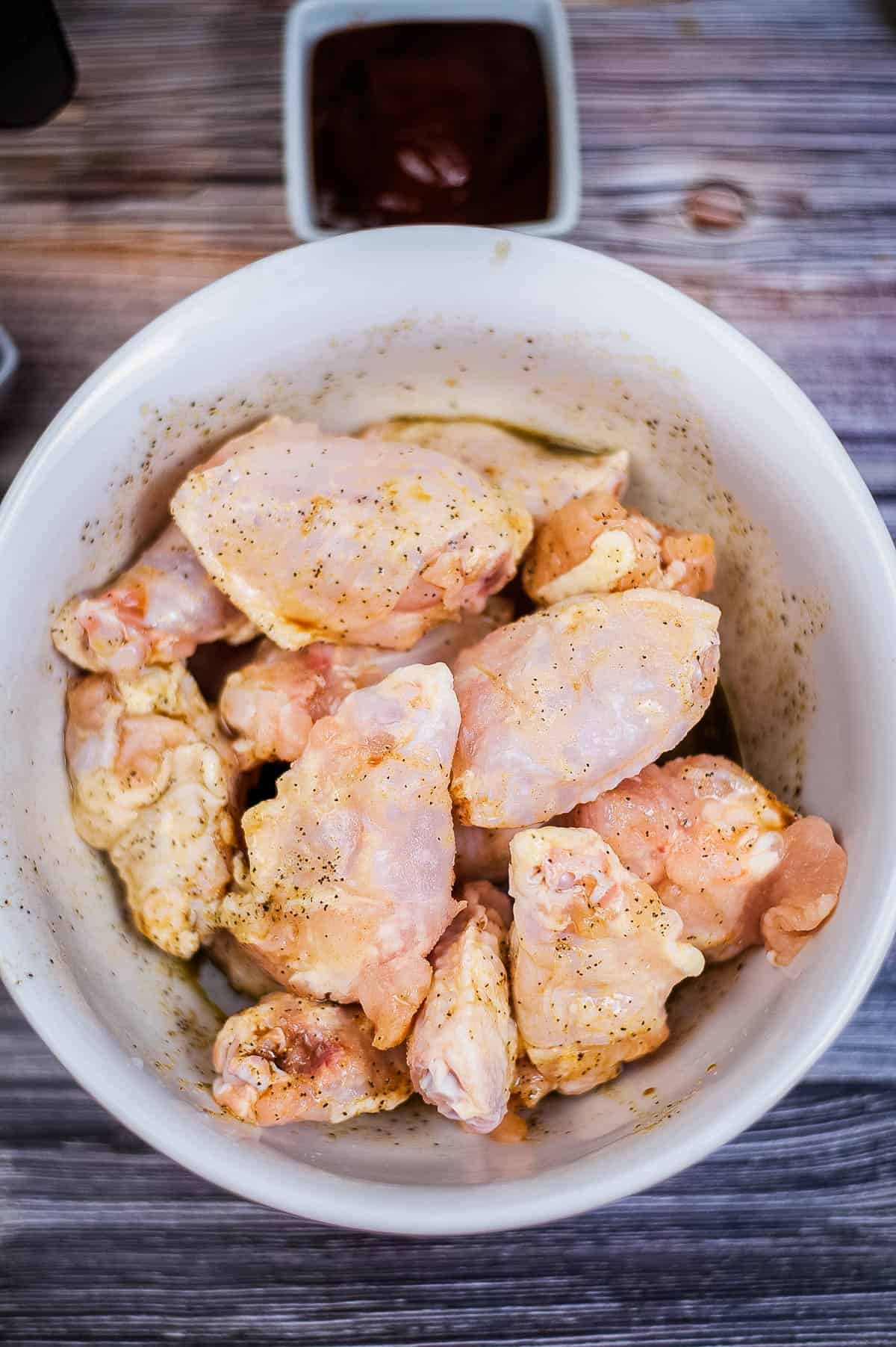 Chicken breasts on a white bowl, air fried and served on a wooden table.