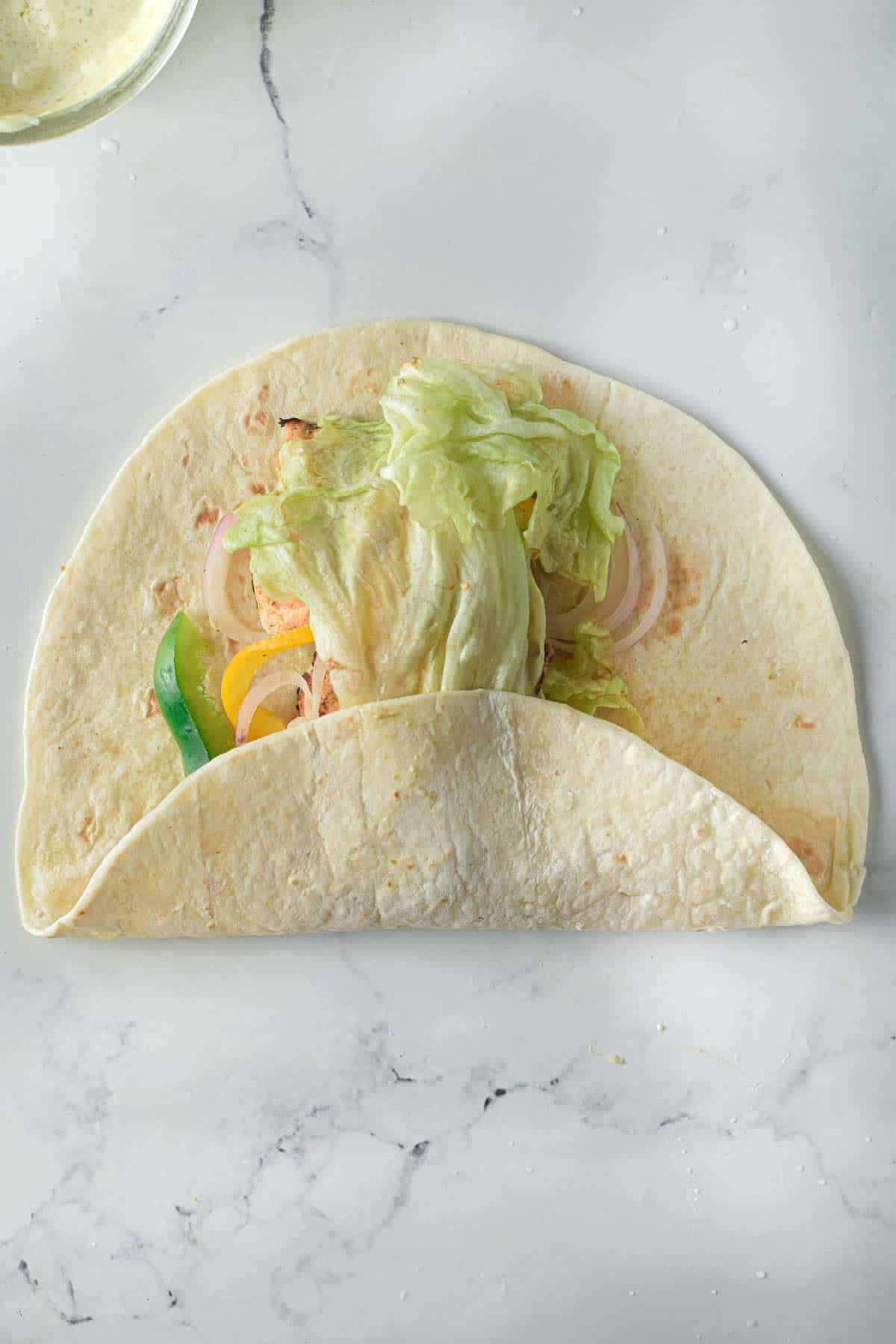 A chicken tikka wrap cooked in an air fryer on a white surface.