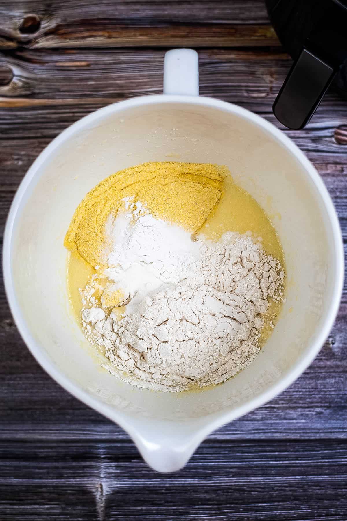 A white bowl filled with flour and other ingredients for air fryer cornbread.