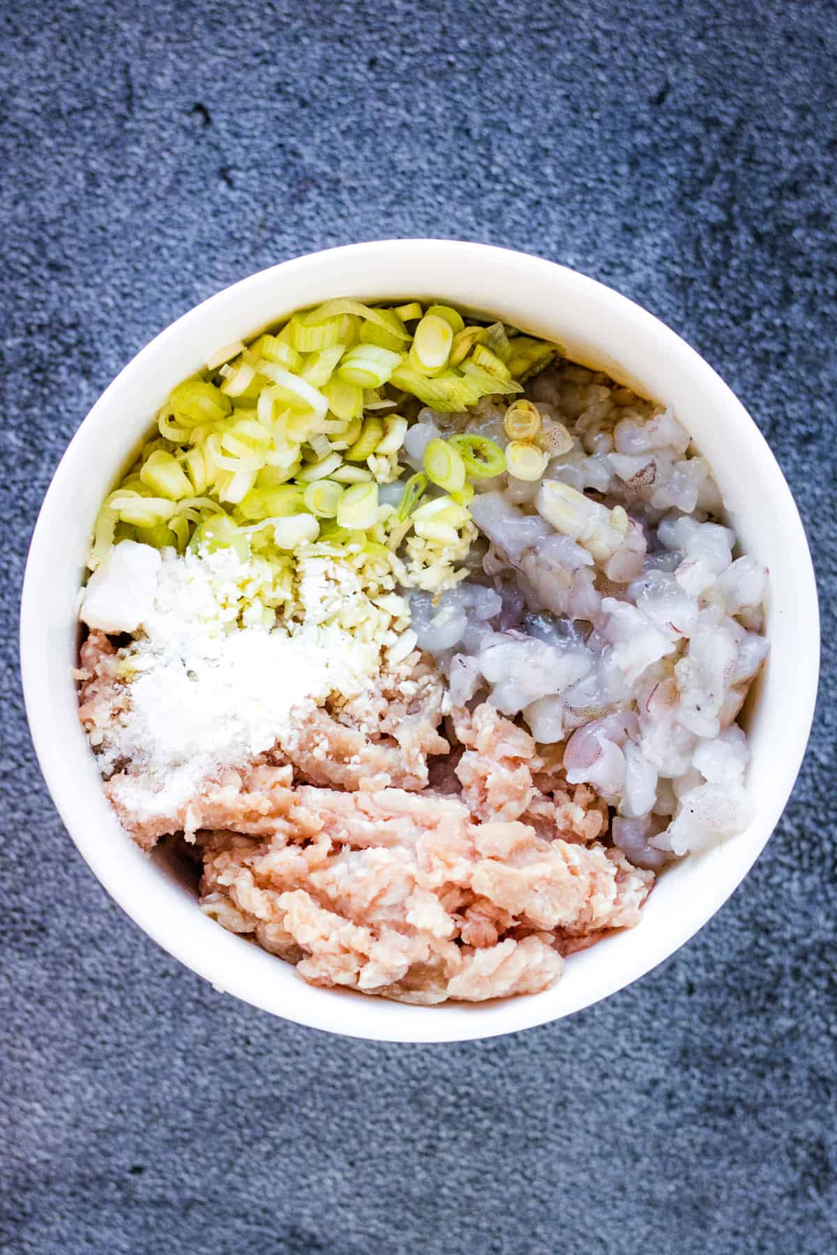 A white bowl filled with tuna, rice and vegetables.