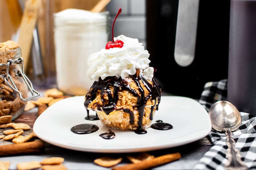 Low angle shot of fried ice cream with chocolate sauce and whipped cream.