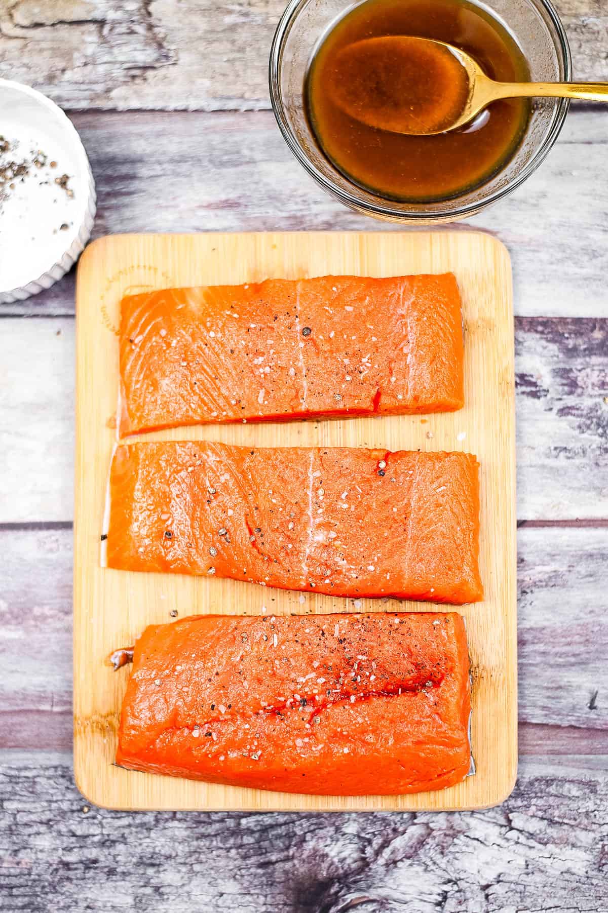 Three pieces of air fryer salmon on a wooden cutting board.