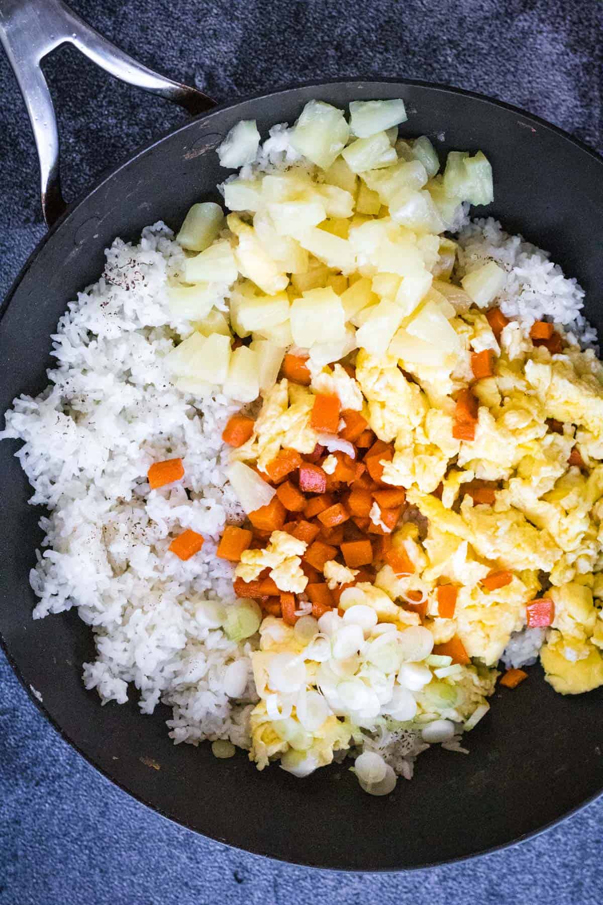 A wok filled with pineapple fried rice and vegetables.