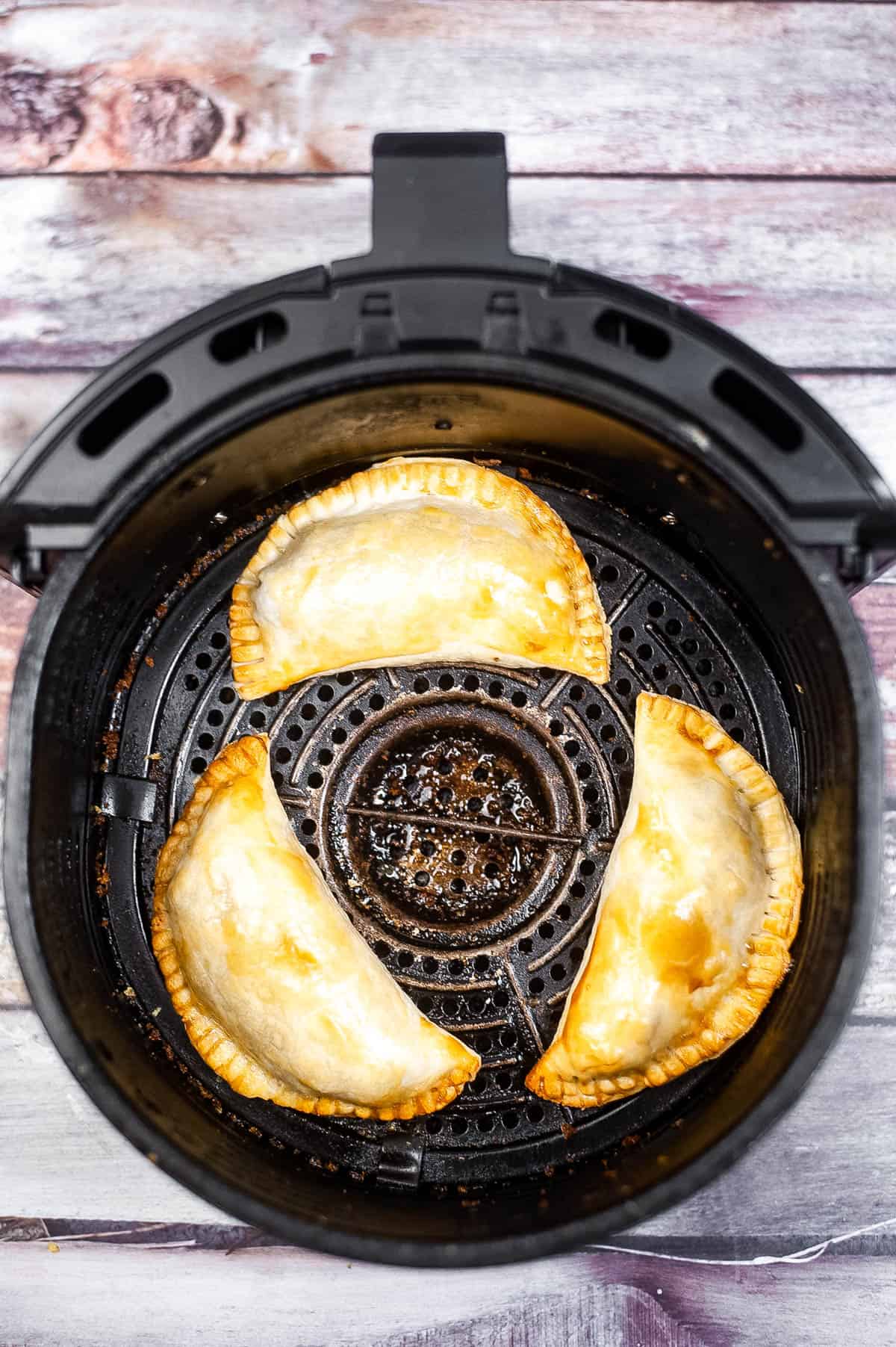 An air fryer filled with empanadas.