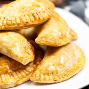 Close up shot of a pile of empanadas on a plate.
